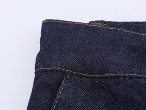 Dettaglio del tessuto denim blu scuro e cuciture a contrasto gialle sui pantaloni