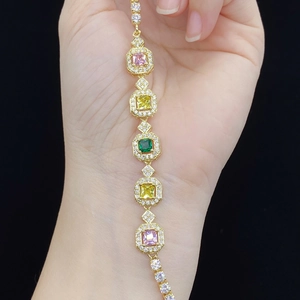 Makro-Detail des vergoldeten Armbands mit quadratischen rosa und gelben Steinen und Kristallen