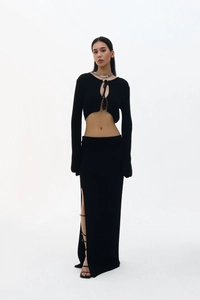 Détail d'un ensemble en maille noire avec haut lacé et jupe à fente haute avec boucles