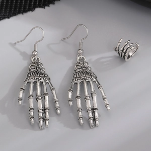 Detailed view of vintage silver skeleton hand earrings and ear cuff on gray background