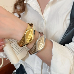 Detail shot of wide metallic irregular pleated bangles in gold and silver finish