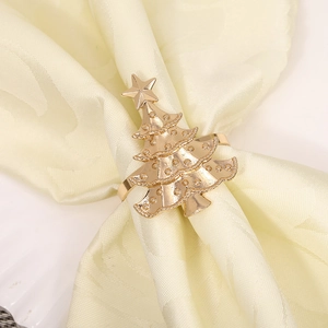 Detailed view of a golden Christmas tree metal napkin ring on a light yellow fabric cloth