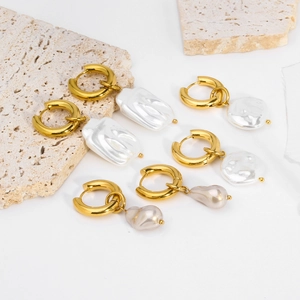 Detailed macro view of 18K gold earrings with baroque pearls on stone display