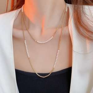 Gros plan d'un collier double épaisseur en or avec perles blanches délicates pour femmes