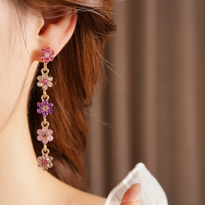 Close-up of pink and purple floral tassel earrings with sparkling crystals on ear