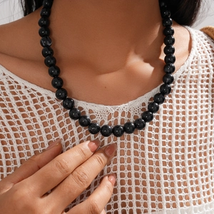 Detail shot of vintage acrylic beaded necklace featuring glossy black round beads on a model