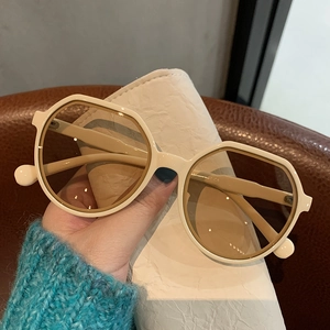 Detailed macro view of beige geometric retro sunglasses with light brown lenses and frame