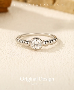 Macro shot of silver bubble ring with round moissanite in bezel setting and bead band