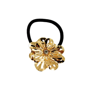 Détail d'une fleur dorée avec cristal montée sur un élastique noir pour les cheveux