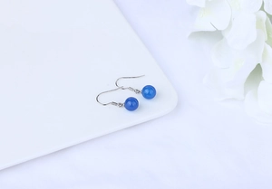 Detailed macro view of smooth blue agate beads hanging on silver fishhook earrings