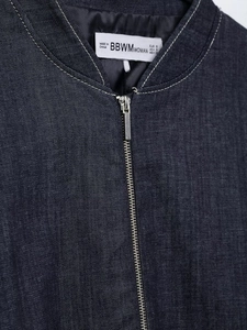 Detail of deep blue denim bomber jacket showing metal zipper and brand neck label