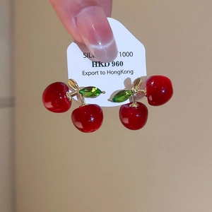 Detailed close-up of cherry stud earrings featuring red resin and green crystal leaves