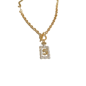 Golden twist chain necklace with number 5 pearl pendant on a clean white background