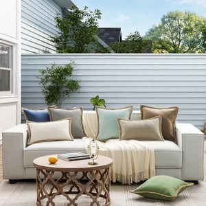 Modern solid linen throw pillow covers with decorative piping on an outdoor sofa