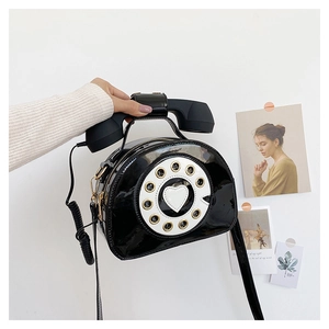 Detailed close-up of a creative vintage black patent leather telephone-shaped handbag