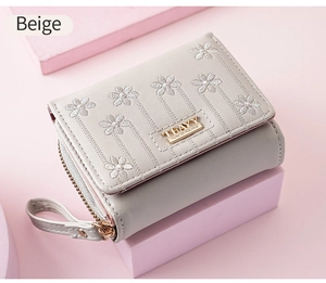 Detailed embroidery of flowers on beige faux leather wallet with metal zipper and buckle