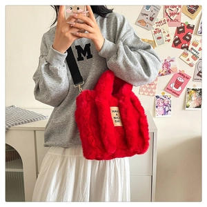 Macro detail of red plush tote bag showing soft faux fur texture and black strap