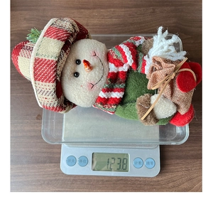 Detailed view of the 123.8g lightweight Christmas snowman plush figurine on a digital scale