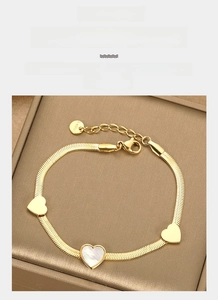 Detail of gold snake chain bracelet featuring pearl shell hearts and polished charms