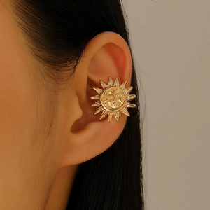 Detail of a bright gold sun god ear cuff featuring an embossed sun face and rays