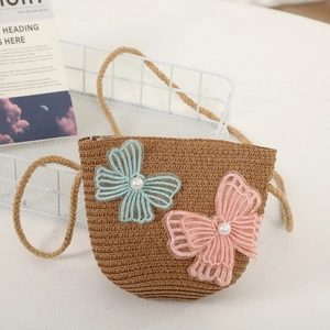 Detail of girls' brown straw shoulder bag with delicate lace butterfly and pearl accents