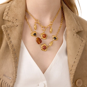 Layered gold chain necklace featuring resin heart and leaf charms on model