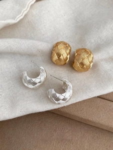 Macro view of woven texture metal C-shaped earrings in gold and silver finishes