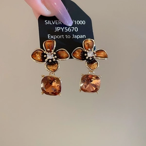 Detailed shot of amber flower earrings with square crystal pendant and gold finish