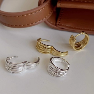 Detailed macro view of multi-layer striped C-shaped earrings in polished gold and silver