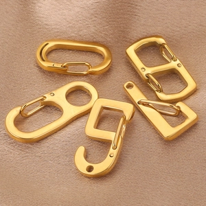 Polished gold stainless steel lobster clasps in various shapes on silk background