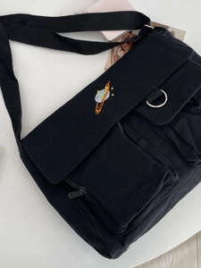 Minimalist black canvas messenger bag with planet embroidery and adjustable shoulder strap