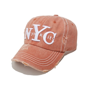 Detail of vintage washed rust red baseball cap with white NYC 3D embroidery and distressed holes