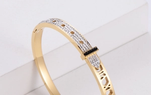 Macro detail of gold geometric hollow bangle with Roman numerals and pavé diamonds