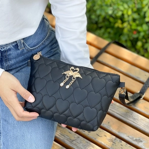 Black quilted crossbody bag with heart patterns and golden swan clasp in hand