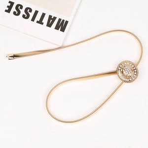 Détail de la ceinture dorée en métal à ressort avec boucle sertie de strass