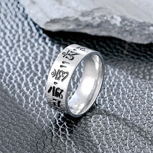 Macro shot of silver titanium steel ring with engraved Buddhist Om Mani Padme Hum script