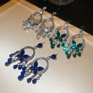 Detailed macro view of crystal butterfly hoop earrings with drop tassels in three colors