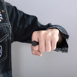Close-up of a matte black oval signet ring for men worn on a hand in casual style