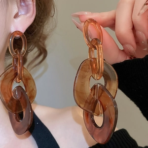 Detail of amber tortoiseshell acrylic drop earrings on model showing glossy texture