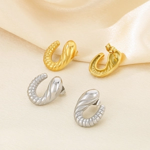 Detailed macro shot of 18K gold and silver plated twisted hoop earrings on satin