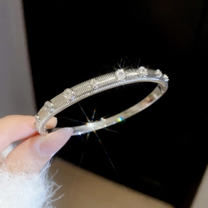 Macro shot of silver textured bangle featuring circular zircon stones and brushed finish