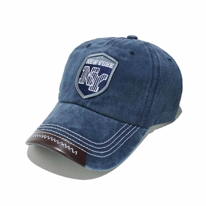 Close-up of navy denim baseball cap featuring NY shield embroidery and leather brim trim