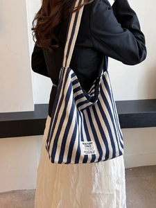 Blue and white striped canvas tote bag shown on model back for casual fashion style