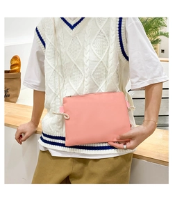 Pink canvas crossbody bag detail with drawstring strap and zipper closure in bakery scene