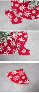 Detail of red plush Christmas tree skirt and stocking with white snowflake patterns
