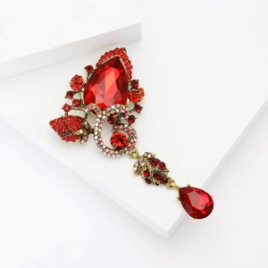 Macro shot of a vintage gold brooch with red teardrop crystal and AB rhinestone details
