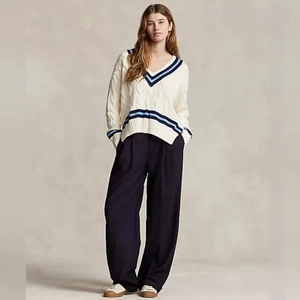 Detail view of v-neck cable knit sweater with navy blue striped cuffs and wide leg pants