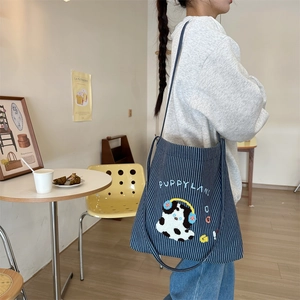 Detail of navy striped canvas tote featuring cute puppy embroidery and Puppyland text