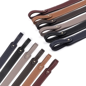 Macro view of multi-color lychee grain leather bag straps with white stitching and gold rivets