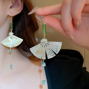 Detailed close-up of fan-shaped Chinese style earrings with green beads and gold tassels